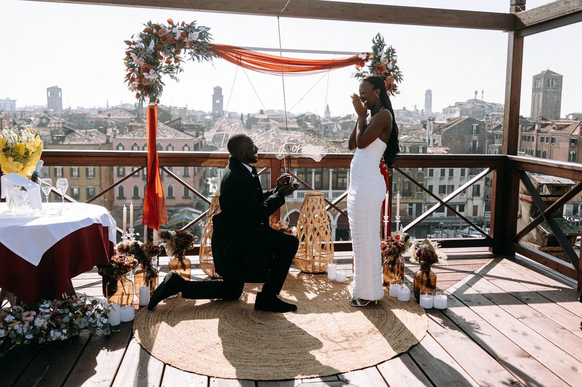 Marriage proposal in Venice – man kneeling on rooftop with Venice panorama view