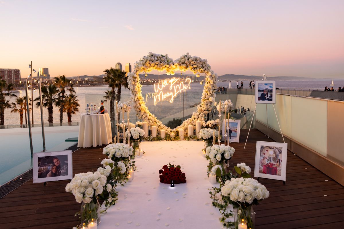 Marriage proposal in Barcelona – rooftop white heart with neon sign and sea view at sunset