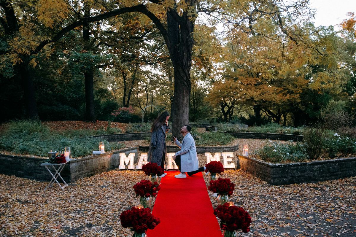 Marriage proposal in Berlin park in autumn – MARRY ME letters with man kneeling for partner