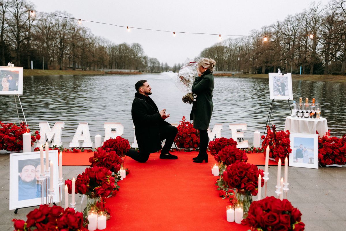 Marriage proposal in Cologne park – lake setting with red roses and MARRY ME arrangement