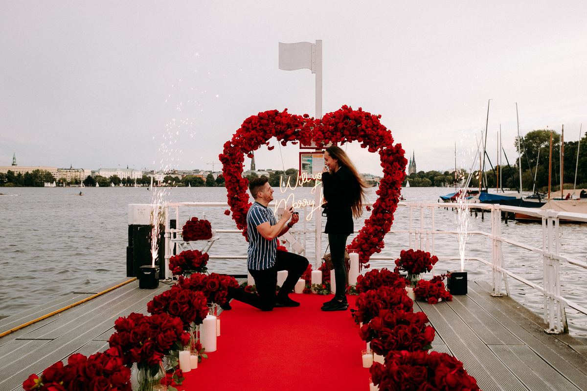 Marriage proposal in Hamburg – Alster lake jetty with red heart, man kneeling and fireworks