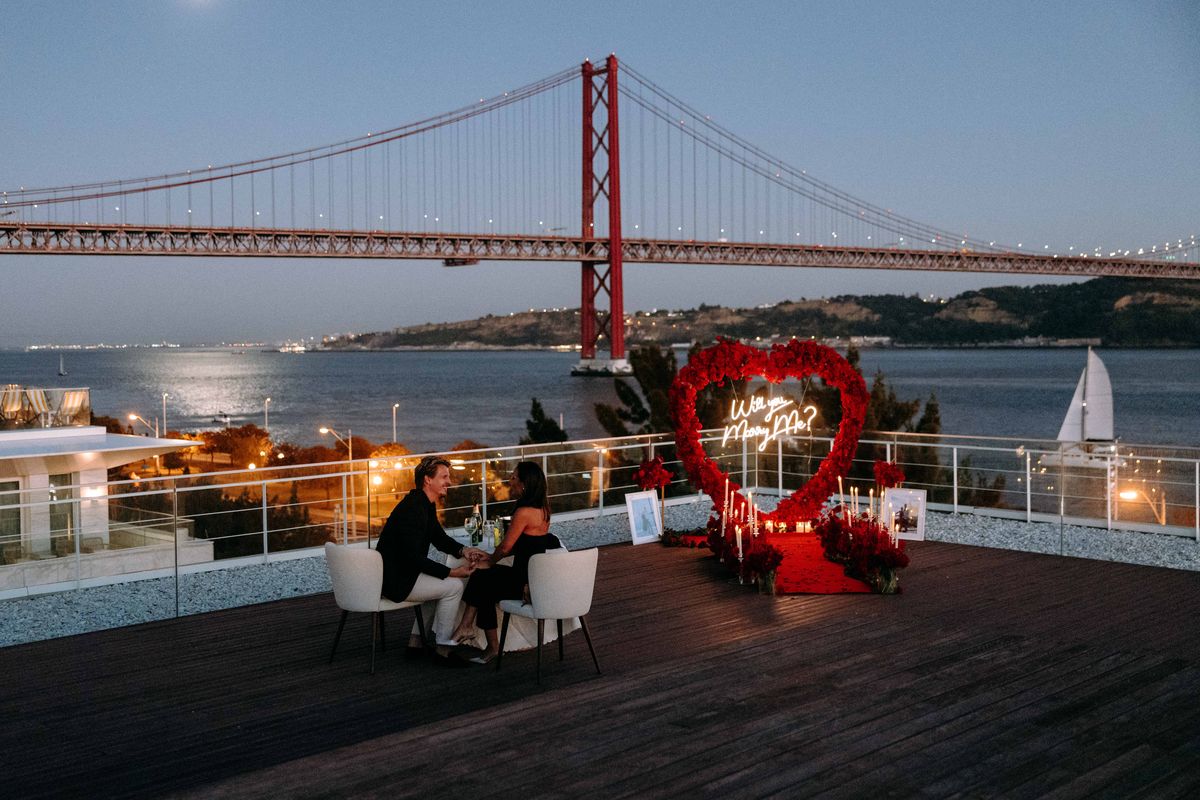 Marriage proposal in Lisbon – April 25th Bridge with red heart and neon sign in the evening