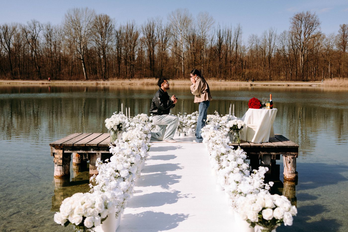 White Blossom proposal on lake jetty – man kneeling with white flower decoration