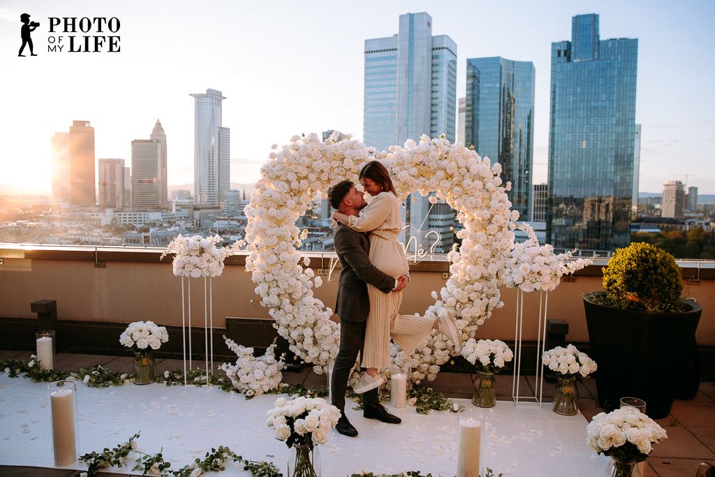 White Elegance proposal on Frankfurt rooftop – couple kissing with skyline view at sunset